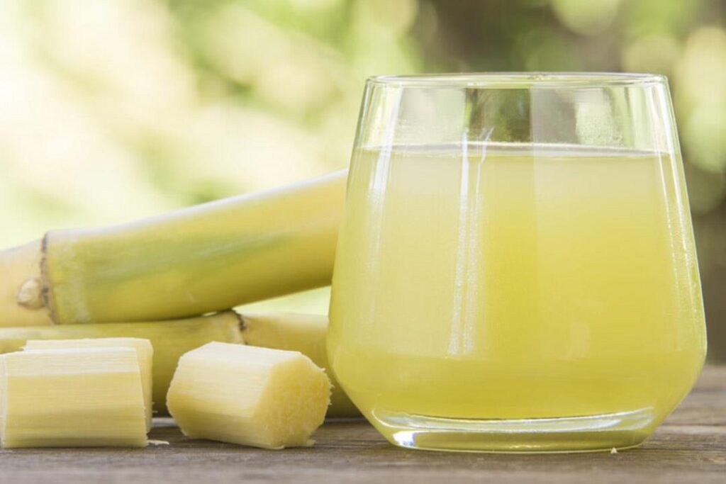 كوب عصير قصب طازج مع عيدان القصب يوضح فوائد عصير القصب للصحة